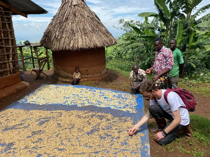 a group of people standing around a blue and yellow rug